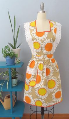 an apron on a mannequin next to a potted plant