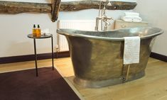 an old fashioned bathtub in a bathroom with wood flooring