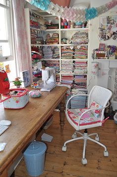 a sewing studio with lots of crafting supplies on the desk and shelves full of fabric