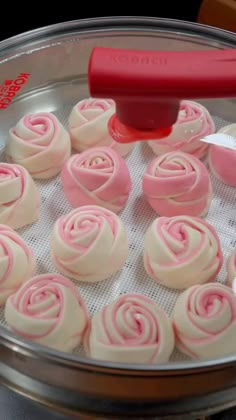 a pan filled with pink and white frosting roses on top of a table next to a red spatula