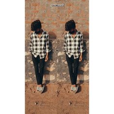 a woman standing in front of a brick wall wearing black and white checkered shirt