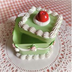 there is a green cake with a cherry on top and white icing around the edges