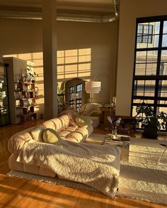 a large living room with wooden floors and lots of light coming in from the windows