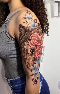 a woman with a wolf and flower tattoo on her arm