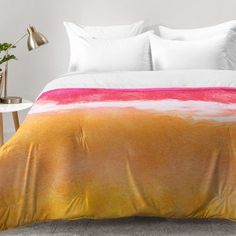 an orange and pink bed spread with white pillows on top of it in a bedroom