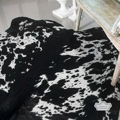 a black and white cowhide rug on the floor next to a table with a bench