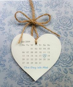 a white heart shaped calendar hanging on a string with twine and burlap