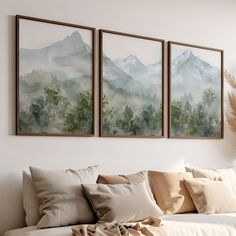 three paintings hang on the wall above a couch in a living room with pillows and blankets