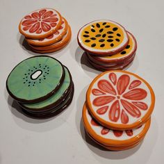 four decorated cookies sitting on top of a white table next to orange slices and kiwis