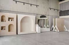 an empty room with several shelves and sculptures on the floor in front of a staircase