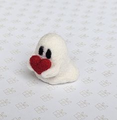 a small white stuffed animal with a red heart on it's nose and eyes