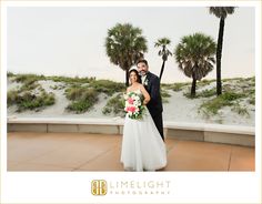 a bride and groom standing in front of palm trees at their wedding reception on the beach