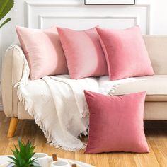 a couch with pink pillows on top of it and a potted plant next to it