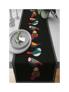 a black table runner with colorful fish on it, along with plates and vases