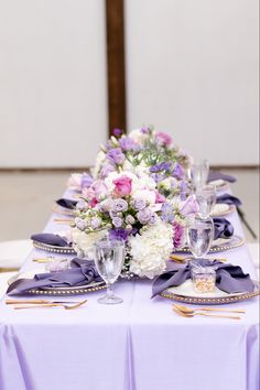 the table is set with purple and white flowers