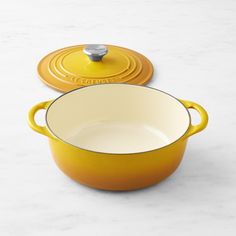 two yellow pans sitting on top of a white counter next to an orange one