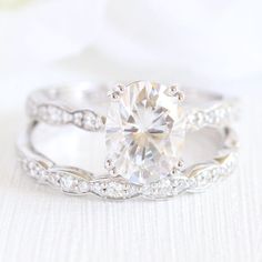 a close up view of a diamond ring on a white surface with flowers in the background