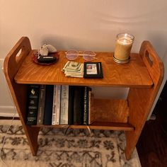 a wooden table topped with books next to a glass filled with liquid and a candle