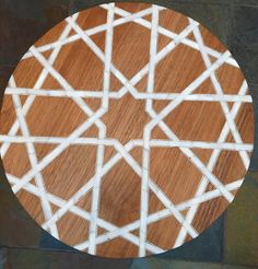 a round wooden table with white lines on the top and brown wood in the middle