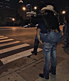 a man in a cowboy hat hugging a woman on the street