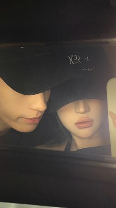 two people wearing hats are looking at their cell phones in the mirror while they both look into each other's eyes