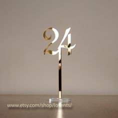 a golden cake topper with the number twenty four in it's center on a wooden table