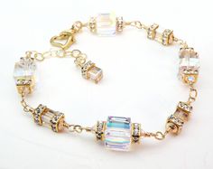 Beautiful modern wedding bracelet is handmade with very sparkly Swarovski crystals in a clear hue. Accented with gold Swarovski crystal crowns and small champagne hued cubes. Set in 14k gold filled findings. Opulent bracelet perfect for brides on wedding days, mother of the bride, or just days you want to sparkle more than usual. A thoughtful gift for a woman born in April since diamond is her birthstone. Bracelet Details: - Choose sterling silver or 14k gold filled - Bracelet is adjustable for Dazzling Gold Crystal Bracelet For Anniversary, Gold Sparkling Crystal Bracelet For Anniversary, Sparkling Gold Bracelets For Wedding, Gold Sparkling Crystal Bracelet For Weddings, Gold Sparkling Bracelets For Wedding, Dazzling Gold Crystal Bracelet, Gold Crystal Bracelet With Bling For Wedding, Gold Crystal Wedding Bracelet With Bling, Sparkling Gold Bracelets For Anniversary