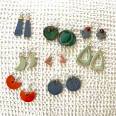 a collection of earrings on a white towel with beads and charms hanging from them,