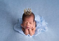 a newborn baby wearing a golden crown on top of it's head in a blue blanket