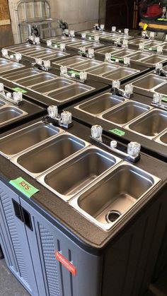 several stainless steel sinks are lined up in a row on the floor next to each other