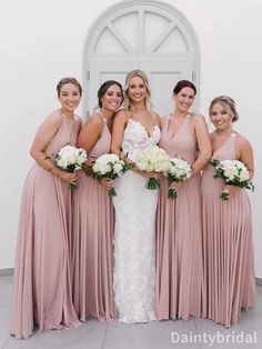 a group of women standing next to each other in front of a white door wearing dresses