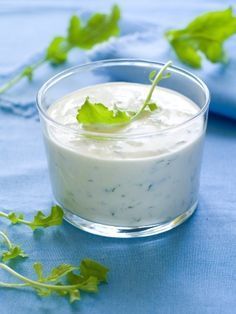 a small glass bowl filled with yogurt and garnished with green leaves