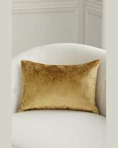 a gold pillow sitting on top of a white chair