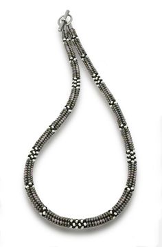 a long beaded necklace is shown on a white background with the beads in black and silver