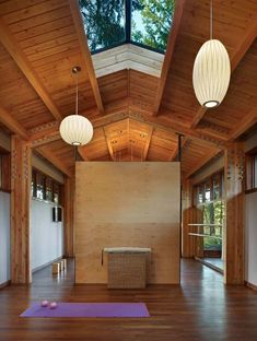 an empty room with wooden floors and two lamps hanging from the ceiling, along with yoga mats on the floor