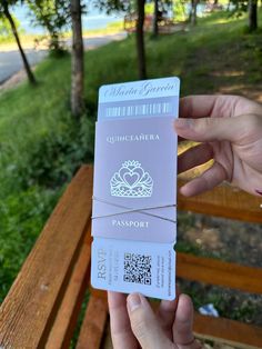 a person holding up a pink card with a qr code attached to it in front of a park bench