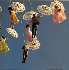 some people are hanging upside down with umbrellas