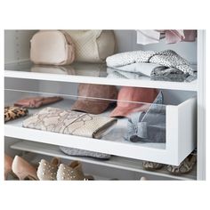 several pairs of shoes and purses are on shelves in a closet with white shelving