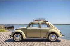 an old vw bug is parked on the dock