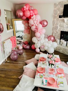 a table set up for a party with pink and white balloons