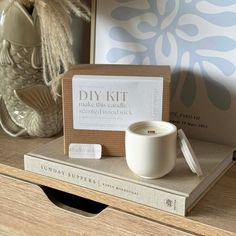 a white candle sitting on top of a wooden table next to a box and some books