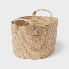 a large round basket with handles on the bottom and sides, made out of jute