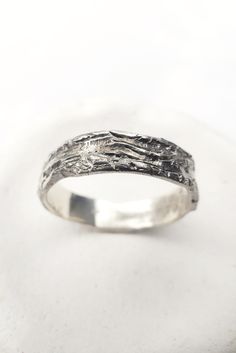 a white gold ring with an intricate design on the side, and a textured band