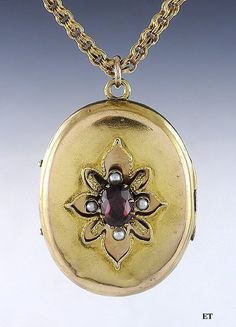 Presented is a fabulous 14 karat gold Victorian American locket pendant with chain. This piece dates to around the 1870s. The locket is oval form with a stylized flower on the front. The center of the 'flower' is an oval faceted garnet, which is a rich red-pink stone. Surrounding the garnet are four real seed pearls. The interior of the locket has the original bezel and glass on each side, perfect for a photo, a lock of hair, or other memento. There is enough space behind the glass for folded pa Pearl Locket, Lock Of Hair, Small Charms, Pink Stone, Antique Jewellery, Ornament Gifts, Jewelry Ideas, Locket, Jewelry Art