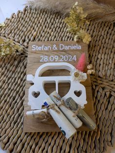 a wooden sign with scissors and some other items on it next to dried flowers in the background