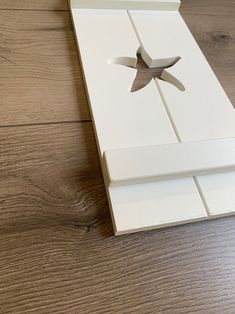 an open white box sitting on top of a wooden floor next to a pair of scissors