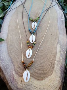 three necklaces with shells and beads on a tree stump