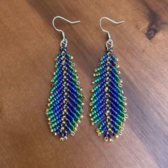 a pair of beaded earrings sitting on top of a wooden table