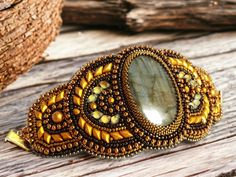 a close up of a brooch on a wooden table next to a piece of wood