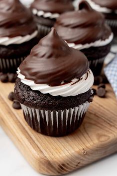 chocolate cupcakes with white frosting and chocolate chips on a cutting board, ready to be eaten